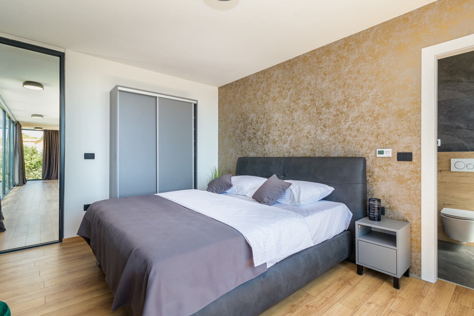 Bedroom with a gold accent wall and ensuite bathroom