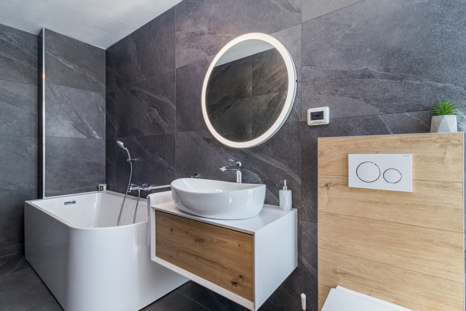 Bathroom with a round backlit mirror and freestanding tub