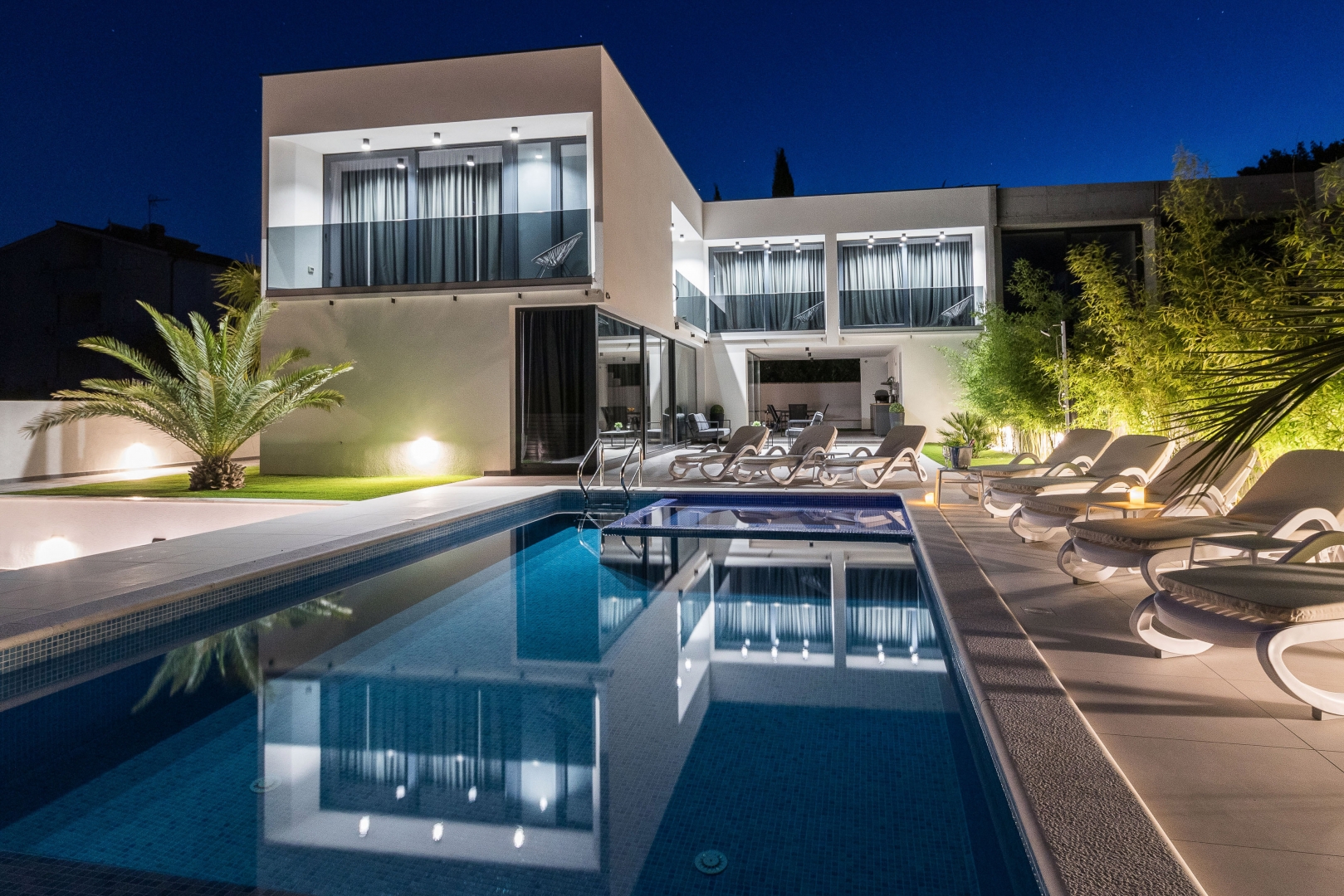 Villa exterior and pool lit up at night